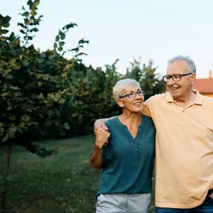 Happy senior couple enjoying while walking embraced in their backyard.
