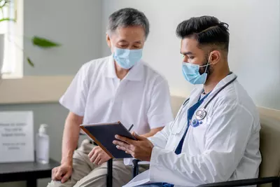 A Doctor Reviews a Patient's Chart with Him on a Tablet in an Exam Room.