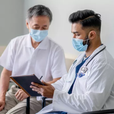 A Doctor Reviews a Patient's Chart with Him on a Tablet in an Exam Room.