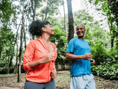 A man and woman running together in the woods.