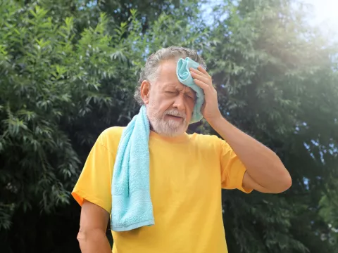 A Man Wipes the Sweat From His Forehead on a Hot Summer Day