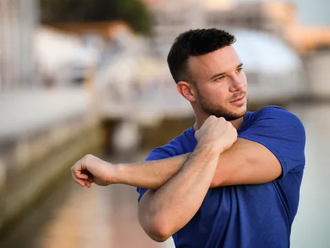 A young man stretching outdoors.