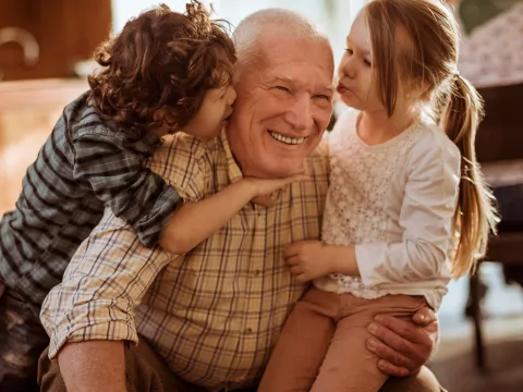 Children greeting Grandpa with a group hug.