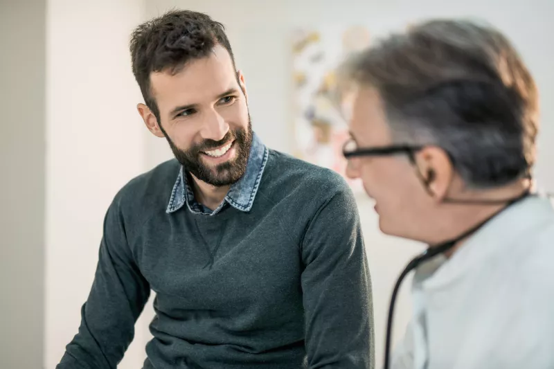 A dark haired and bearded adult man with a male Doctor.