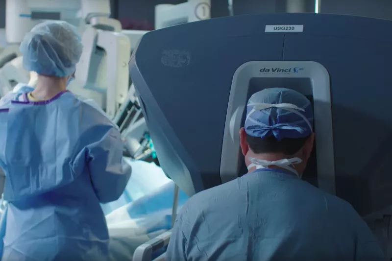 Surgeon and nurse around the da Vinci Robot in a surgery room