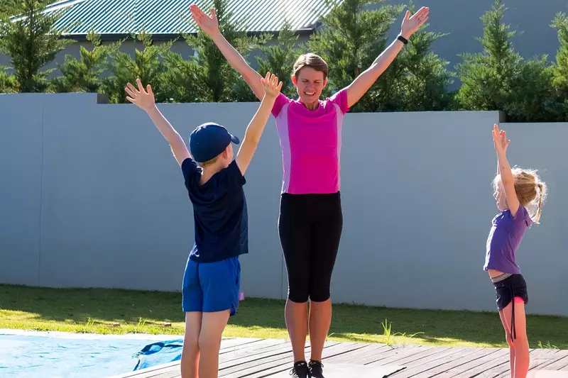 A mom does PE at home with her kids.