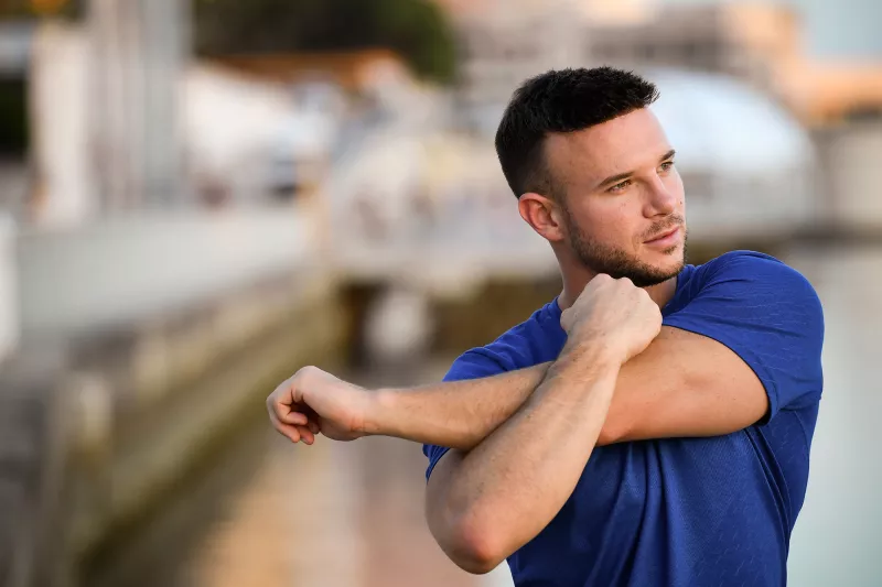 A young man stretching outdoors.