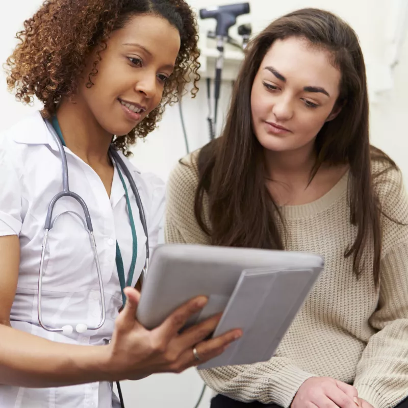 A nurse shows a young woman her test results from a preventive screening.