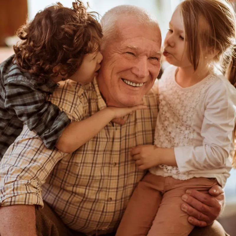 Children greeting Grandpa with a group hug.